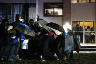 People in a residential building watch as demonstrators gather Tuesday, April 13, 2021, near the Brooklyn Center (Minn.) Police Department to protest Sunday's fatal shooting of Daunte Wright during a traffic stop. (AP Photo/John Minchillo)