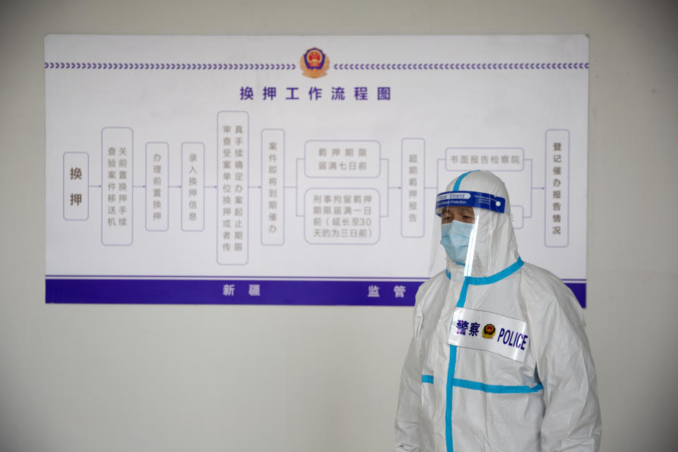 A security officer in a protective suit stands in front of a chart at the visitors' hall at the Urumqi No. 3 Detention Center in Dabancheng in western China's Xinjiang Uyghur Autonomous Region on April 23, 2021. Urumqi No. 3, China's largest detention center, is twice the size of Vatican City and has room for at least 10,000 inmates. (AP Photo/Mark Schiefelbein)