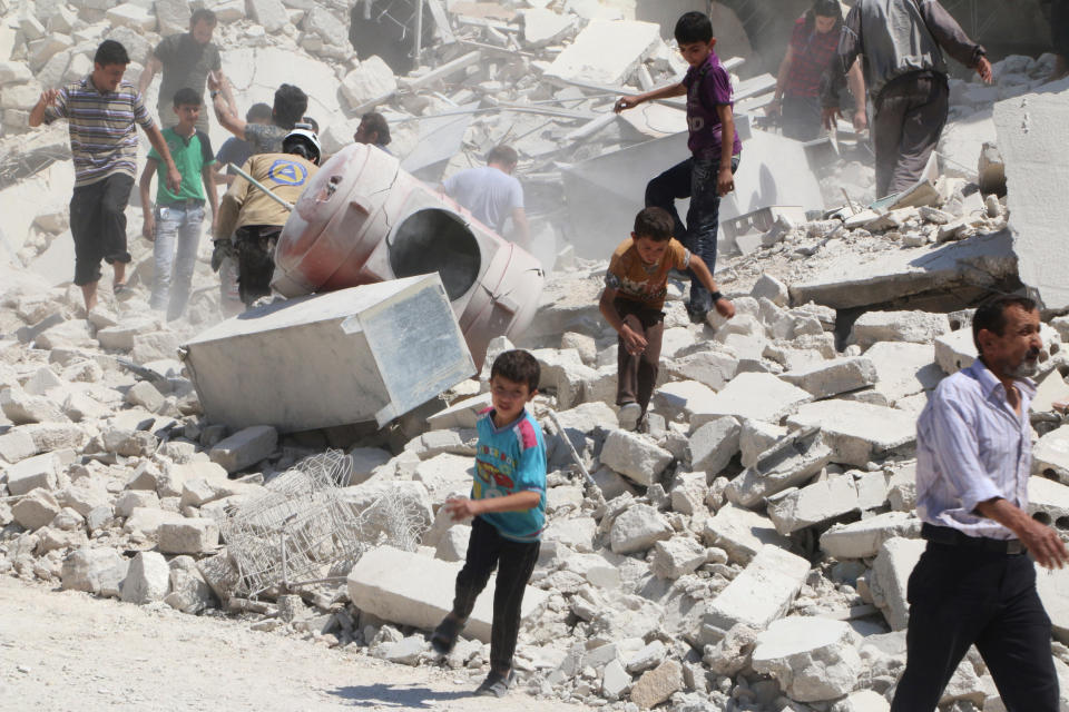 People walk on the rubble of a site hit by an airstrike in the rebel held area of Aleppo's al-Marjeh neighborhood, Syria on June 6, 2016.