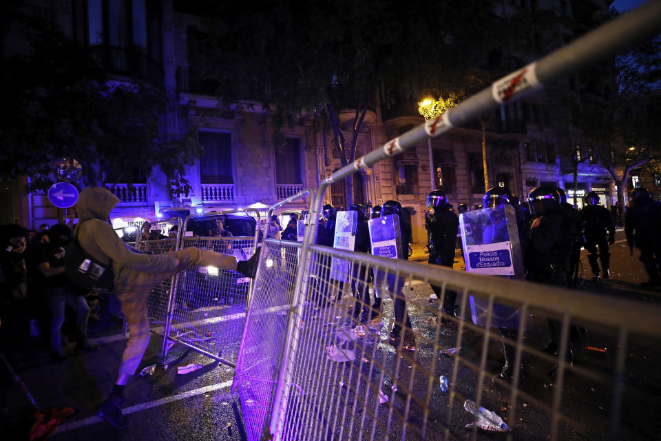 A protestor kicks a fence outside the Spanish Government Office in Barcelona, Spain, Tuesday, Oct. 15, 2019. Spain's Supreme Court on Monday convicted 12 former Catalan politicians and activists for their roles in a secession bid in 2017, a ruling that immediately inflamed independence supporters in the wealthy northeastern region. (AP Photo/Emilio Morenatti)