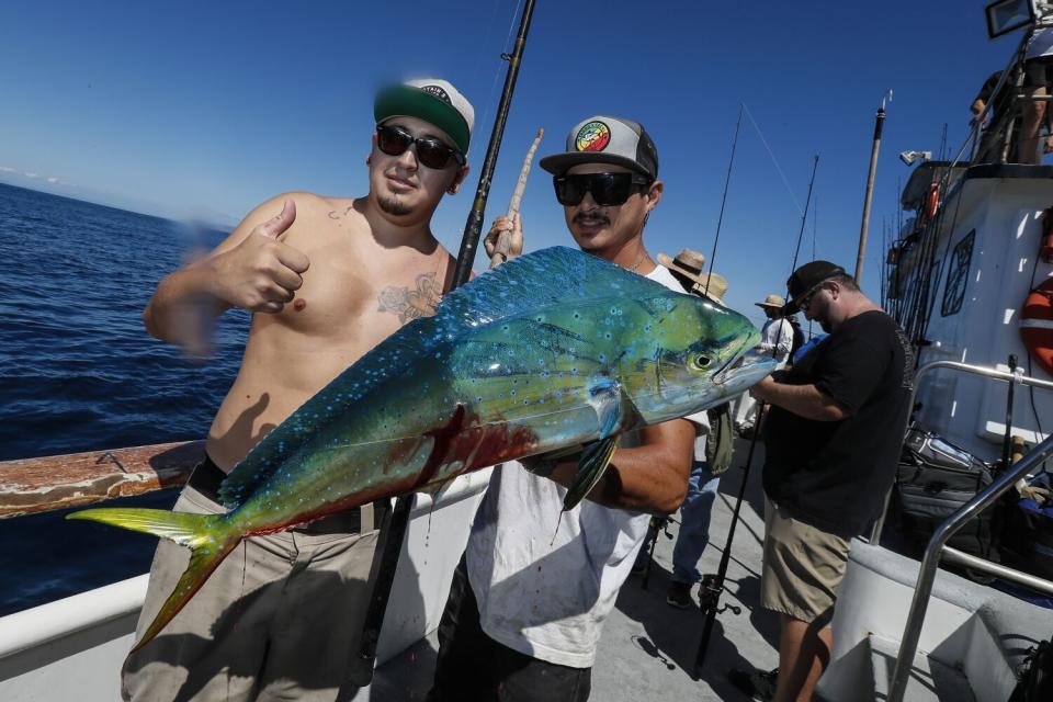 Fisherman Randy Roa shows off his catch with Enterprise fishing boat crew member Easton Ito.