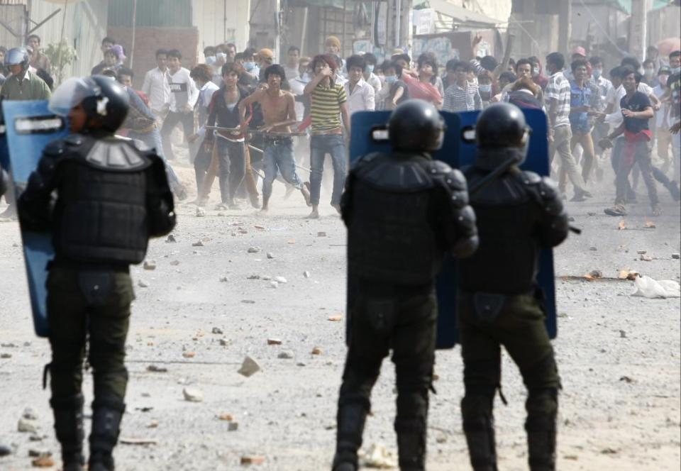 Cambodia garment workers throw stones at riot police during a strike near a factory on the Stung Meanchey complex on the outskirts of Phnom Penh, Cambodia, Friday, Jan. 3, 2014. At least three people were killed Friday when police in Cambodia opened fire to break up a protest by striking garment workers demanding a doubling of the minimum wage, police and human rights workers said.(AP Photo/Heng Sinith)