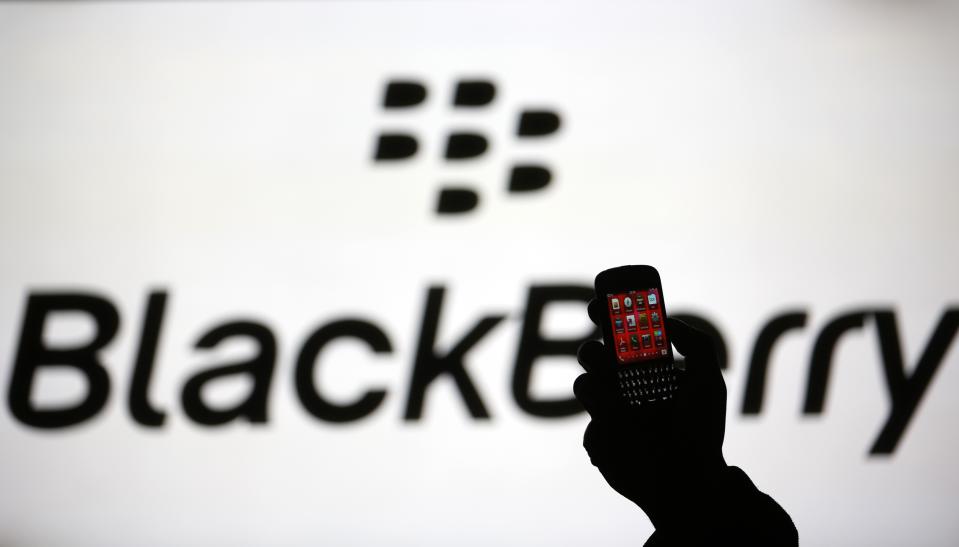 A man is silhouetted against a video screen with the Blackberry logo as he pose with a Blackberry Q10 in this photo illustration taken in the central Bosnian town of Zenica, September 21, 2013. BlackBerry Ltd warned on Friday it expects to report a huge quarterly operating loss next week and that it will cut more than a third of its global workforce, rekindling fears of the company's demise and sending its shares into a tailspin.The company, which has struggled to claw back market share from the likes of Apple Inc's  iPhone and Samsung Electronics Co Ltd's Galaxy phones, said it expects to report a net operating loss of between $950 million and $995 million in the quarter ended Aug. 31, due to writedowns and other factors.   REUTERS/Dado Ruvic (BOSNIA AND HERZEGOVINA - Tags: BUSINESS TELECOMS) - BM2E99L186N01