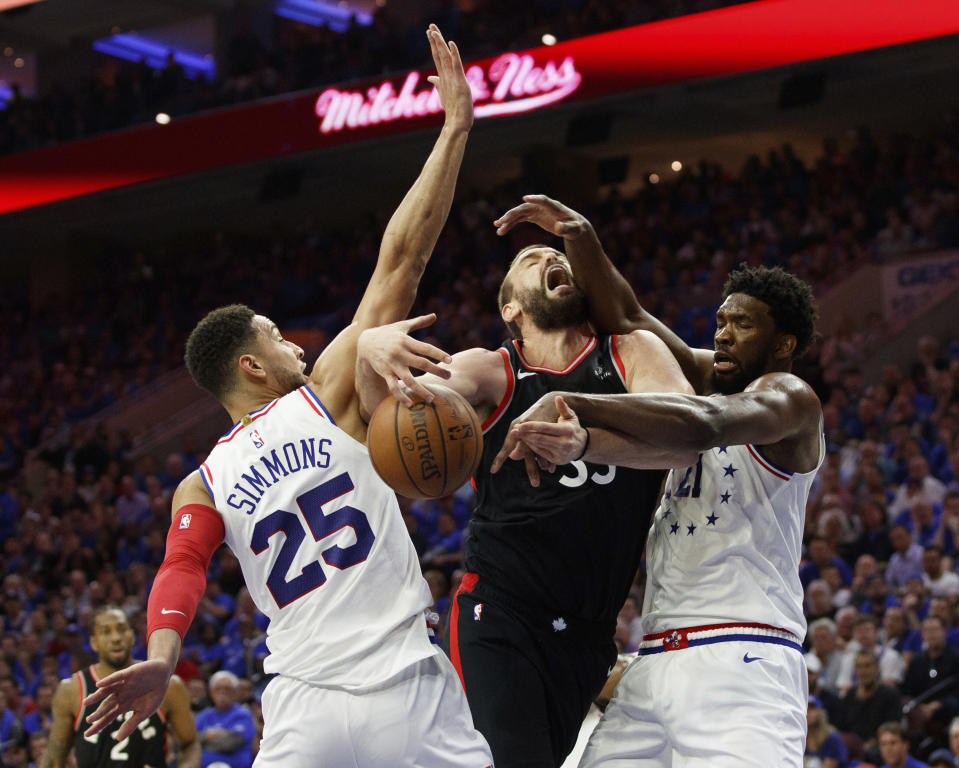 Toronto Raptors' Marc Gasol, center, is fouled by Philadelphia 76ers' Ben Simmons, left, with Joel Embiid, right, also defending during the first half of Game 3 of a second-round NBA basketball playoff series, Thursday, May 2, 2019, in Philadelphia. (AP Photo/Chris Szagola)