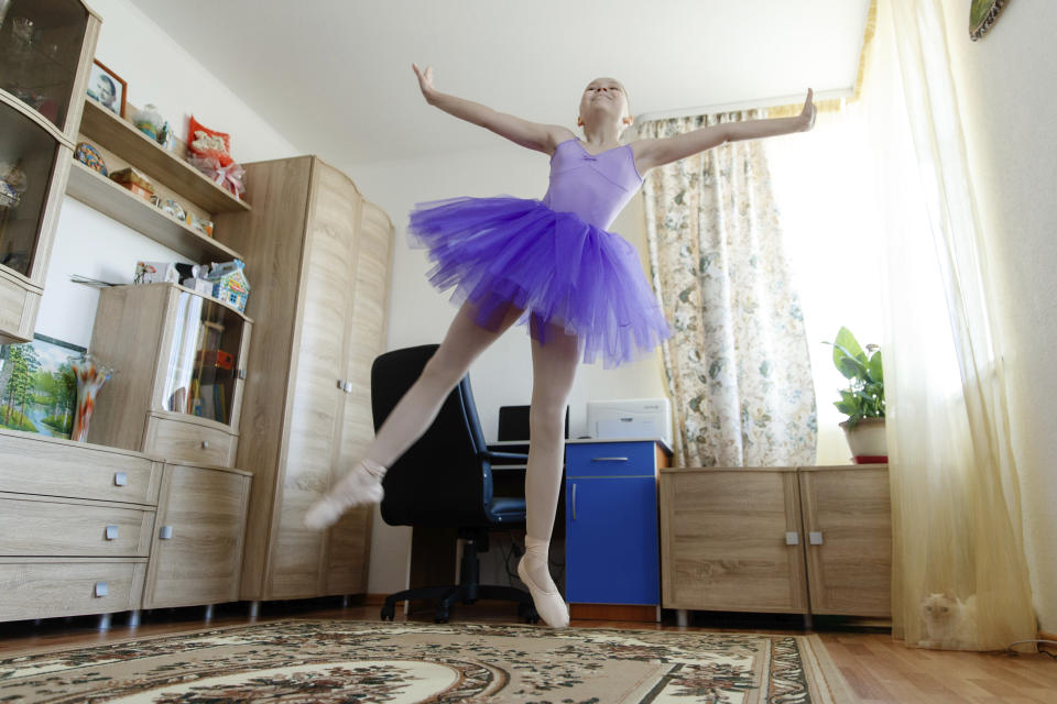 Alexandra Kustova, shows how she dances prior to an interview in her family's apartment in Yekaterinburg, a city in the Urals, Russia on Thursday, May 7, 2020. For 12-year-old Alexandra, self-isolation during the coronavirus pandemic turned out to be a blessing in disguise. Now that all the studies are conducted online, not only does she have more time for her two favorite hobbies _ ballet and jigsaw puzzles _ she spends more time with her family and helps out her grandmother, who lives in the same building two floors down. (AP Photo/Anton Basanaev)