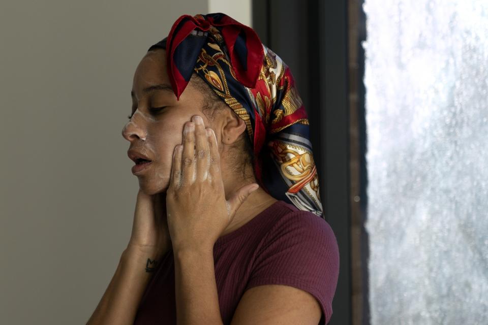 Johnae Strong washes her face as she readies herself and her 10-year-old son and 6-year-old daughter for school and work Friday, Feb. 10, 2023, in Chicago. (AP Photo/Erin Hooley)