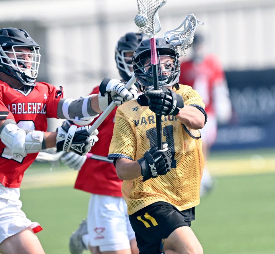 Logan Poulin of Nauset moves toward the Marblehead goal defended by Zander Danforth in the Division 2 Elite Eight boys lacrosse match.