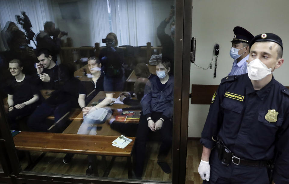 Members of the New Greatness group, who are charged with the organization of an extremist association, sit behind a glass in a courtroom prior to a court hearing in Moscow, Russia, Tuesday, July 14, 2020. Members of an opposition group dubbed New Greatness were arrested in 2018 on charges of creating an extremist group aiming to overthrow the government. The case was widely criticized as an example of politically motivated abuse anti-extremism laws. (AP Photo/Pavel Golovkin)