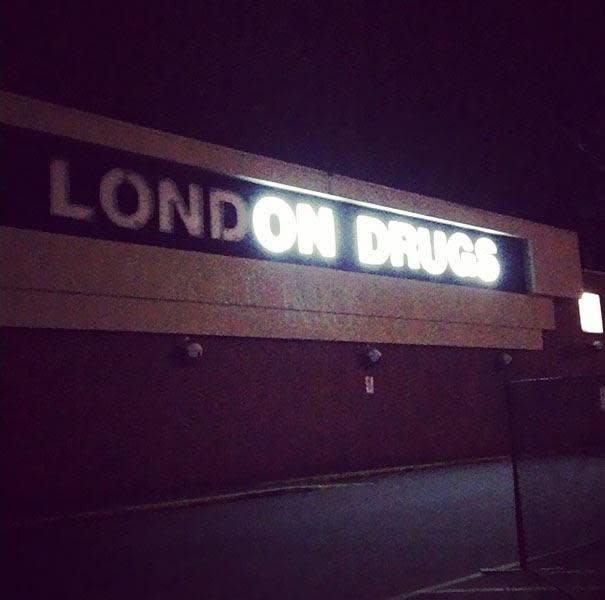 Exterior sign of "London Drugs" store at night but it's partially burnt out and spells "on drugs"