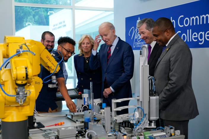 President Joe Biden listens to Bryce Lewis, an industrial systems student at Nash Community College, demonstrate how a yellow robot arm can move during a visit to Nash Community College in Rocky Mount, North Carolina, Friday, June 9, 2023.