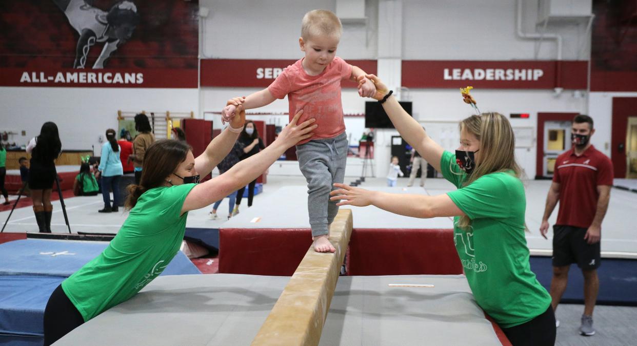 The Crimson Tide gymnastics team hosted the students from the Rise Center for their annual holiday celebration Friday, Dec. 3, 2021. Gymnasts Anna Huber and Mati Waligora help Rise student Silas Edwards walk the balance beam. [Staff Photo/Gary Cosby Jr]
