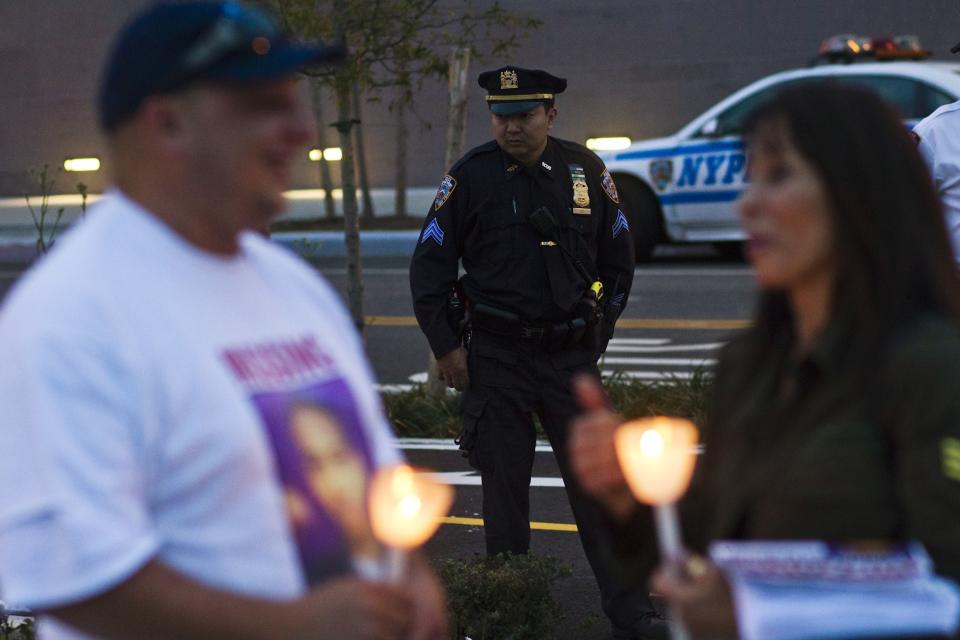 An NYPD officer looks at residents and family members of Avonte Oquendo, who is missing, during his vigil in Queens, New York, October 11, 2013. According to family members, Oquendo, a 14-year-old mute and autistic child, was last seen at his Long Island City school in Queens on October 4. (REUTERS/Eduardo Munoz)