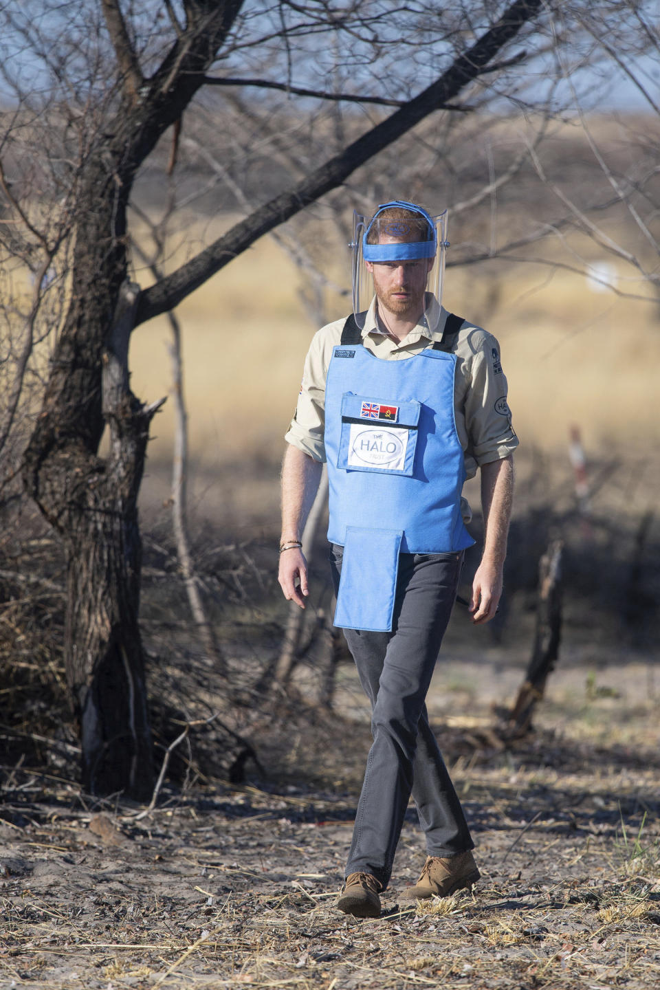 Britain's Prince Harry walks through a minefield in Dirico, Angola, Friday Sept. 27, 2019, during a visit to see the work of landmine clearance charity the Halo Trust, on day five of the royal tour of Africa. Prince Harry is following in the footsteps of his late mother, Princess Diana, whose walk through an active mine field in Angola years ago helped to lead to a global ban on the deadly weapons. (Dominic Lipinski/Pool via AP)