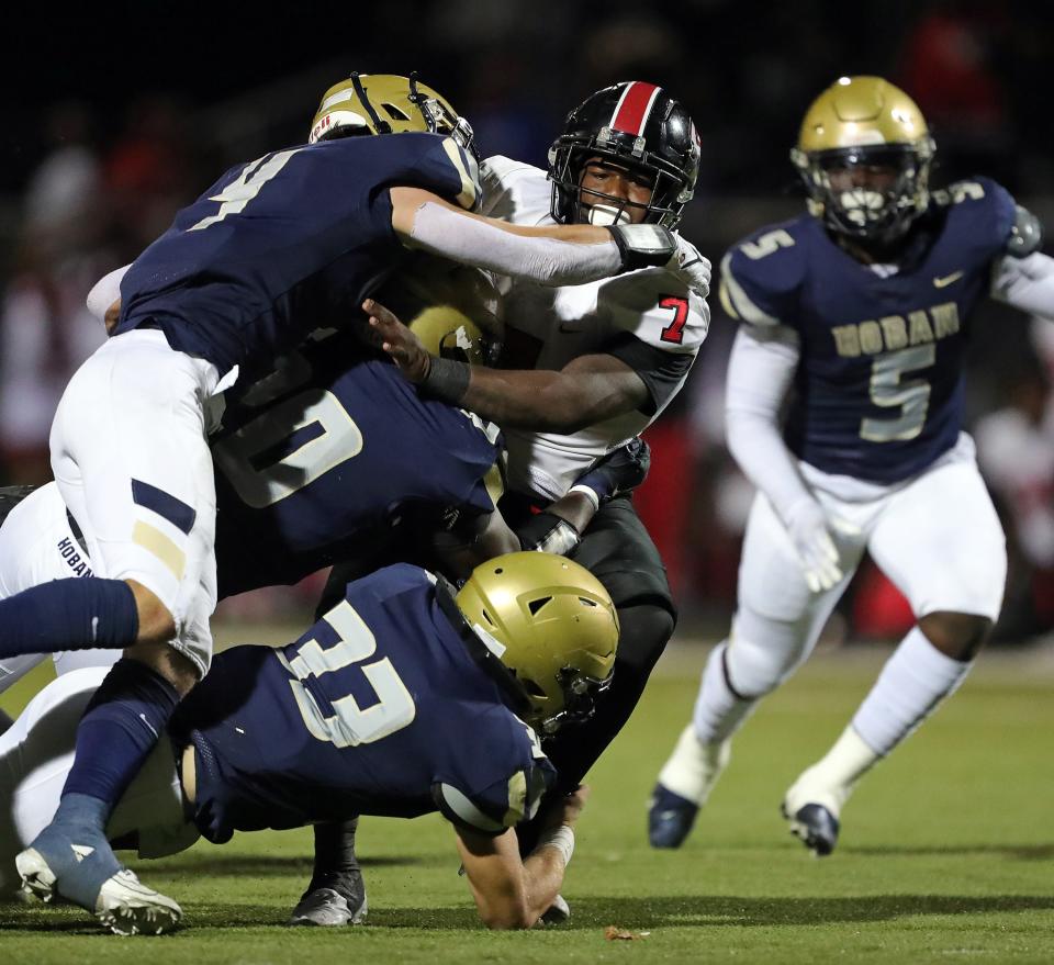 Glenville running back D'Shawntae Jones, center, is brought down by a host of Hoban defenders during the first half of a high school football game, Friday, Oct. 6, 2023, in Akron, Ohio.