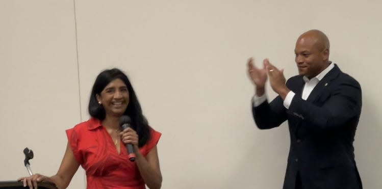 At left, Lieutenant Gov. Aruna Miller speaks to a crowd of cabinet and municipal officials in Ocean City, Maryland on June 27, 2023. At right, Gov. Wes Moore, a Democrat, applauds Miller.