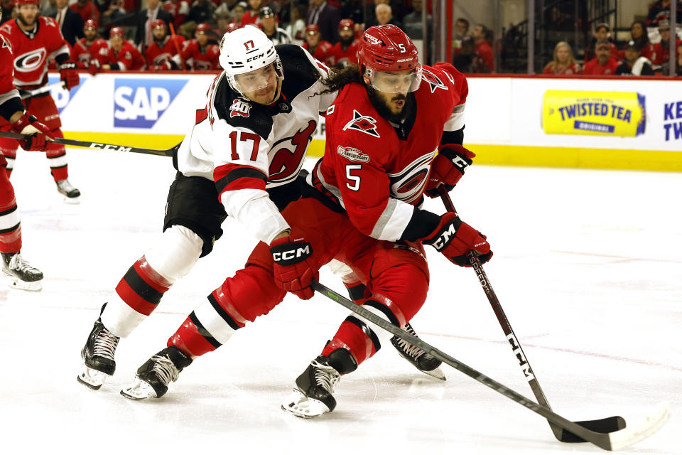 Carolina Hurricanes' Jalen Chatfield (5) controls the puck in front of New Jersey Devils' Yegor Sharangovich (17) during the first period of Game 1 of an NHL hockey Stanley Cup second-round playoff series in Raleigh, N.C., Wednesday, May 3, 2023. (AP Photo/Karl B DeBlaker)