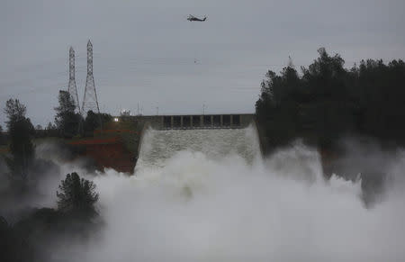 Helicopters carry rocks to the Lake Oroville Dam after an evacuation order was lifted for communities downstream in Oroville, California, U.S. February 15, 2017. REUTERS/Jim Urquhart