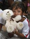 A survivor of Super Typhoon Haiyan holds up a teddy bear which he received from a Christmas gift giving inside an astrodome at Tacloban city, central Philippines December 20, 2013. Super typhoon Haiyan reduced almost everything in its path to rubble when it swept ashore in the central Philippines on November 8, killing at least 6,069 people, leaving 1,779 missing and 4 million either homeless or with damaged homes. REUTERS/Romeo Ranoco (PHILIPPINES - Tags: DISASTER SOCIETY)