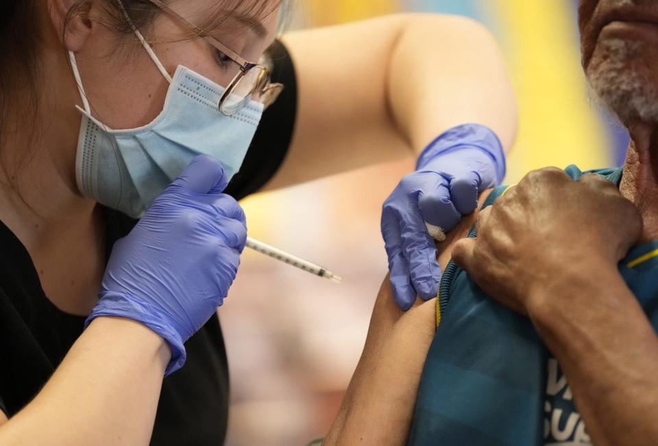 Medical assistant Jessica Lopez gives Antonio Rodriguez his COVID-19 booster shot during a clinic at Promise Arizona's office in Phoenix on Jan. 26, 2022.