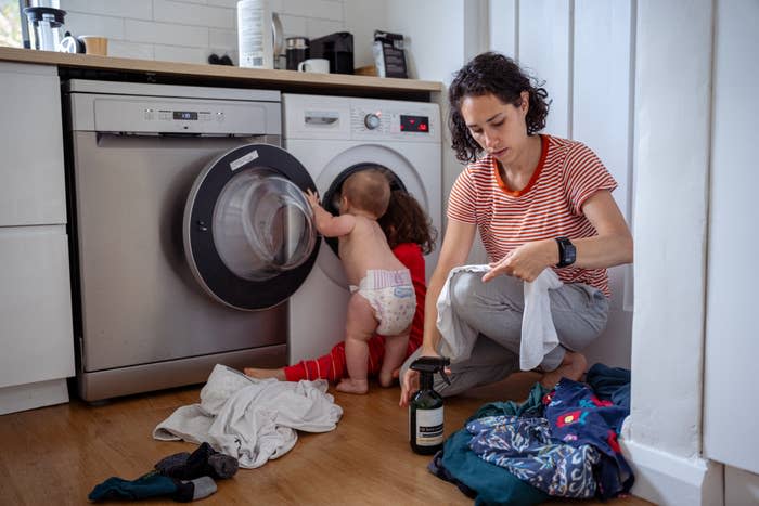 kids taking clothes out of the dryer as the mom sprays the clothes