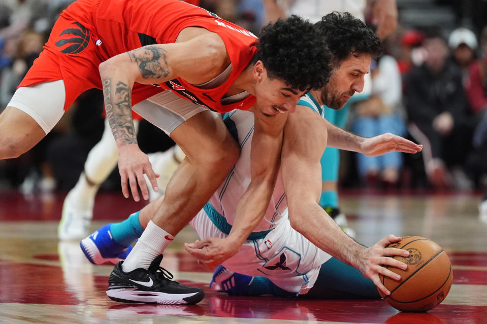 Charlotte Hornets' Vasilije Micić, right, and Toronto Raptors guard D.J. Carton, left, battle for the ball during second-half NBA basketball game action in Toronto, Sunday, March 3, 2024. (Frank Gunn/The Canadian Press via AP)