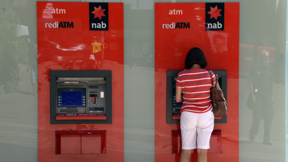 A woman stands at a NAB ATM.