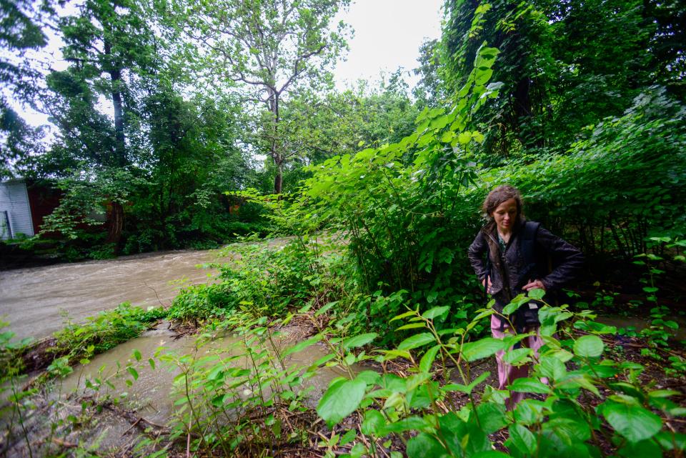Ashley Heath, a person facing homelessness in Brattleboro, Vt., looks over an area where she and others would camp under the Elm Street Bridge near the Whetstone Brook that flooded, Monday, July 10, 2023. In her three months of camping in that spot, this is the worst she has seen the water level. (Kristopher Radder/The Brattleboro Reformer via AP)
