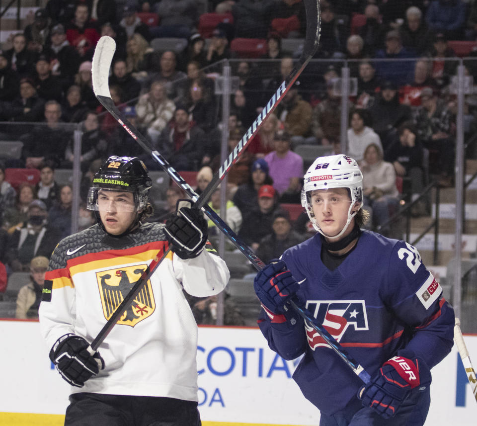 Germany's Philipp Bodoul, left, and United States' Charlie Stramel get their sticks up during second-period IIHF world junior hockey championships quarterfinal match action in Moncton, New Brunswick, Monday, Jan. 2, 2023. (Ron Ward/The Canadian Press via AP)