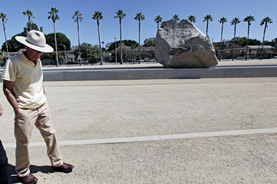 Artist Michael Heizer walks past his sculpture "Levitated Mass" prior to a dedication ceremony featuring a 340-ton granite boulder sitting above a 456-foot-long concrete slot at the Los Angeles County Museum of Art in Los Angeles, on Sunday June 24, 2012. Thousands showed up under sunny skies as the gigantic work titled "Levitated Mass" was unveiled Sunday on the museum’s rear lawn, where it is intended to remain forever. (AP Photo/Richard Vogel)