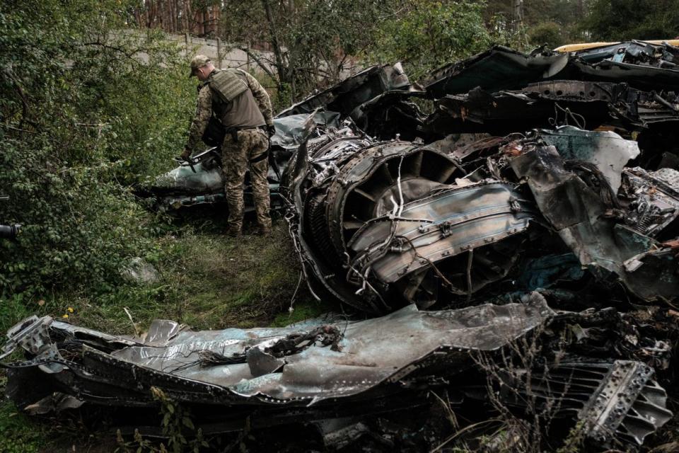 A Ukrainian army's press officer stands next to the debris of Russian air strike aircraft Su-34 at a collection point of destroyed Russian armoured vehicles at an animal feed plant in the recently retaken town of Lyman in Donetsk region, on Oct. 5, 2022, amid the Russian invasion of Ukraine. (Yasuyoshi Chiba/AFP via Getty Images)