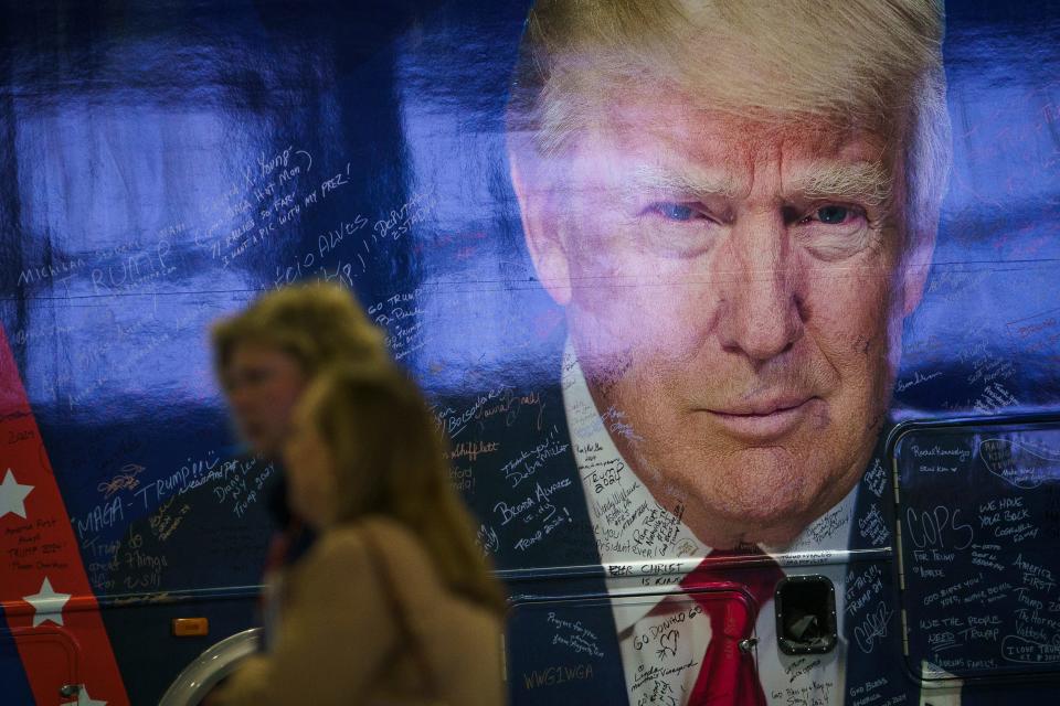 CPAC attendees are seen near a large mural of former President Donald Trump on the side of a bus while waiting for the start of the first of the Conservative Political Action Conference, CPAC 2024, at the Gaylord National Resort & Convention Center.