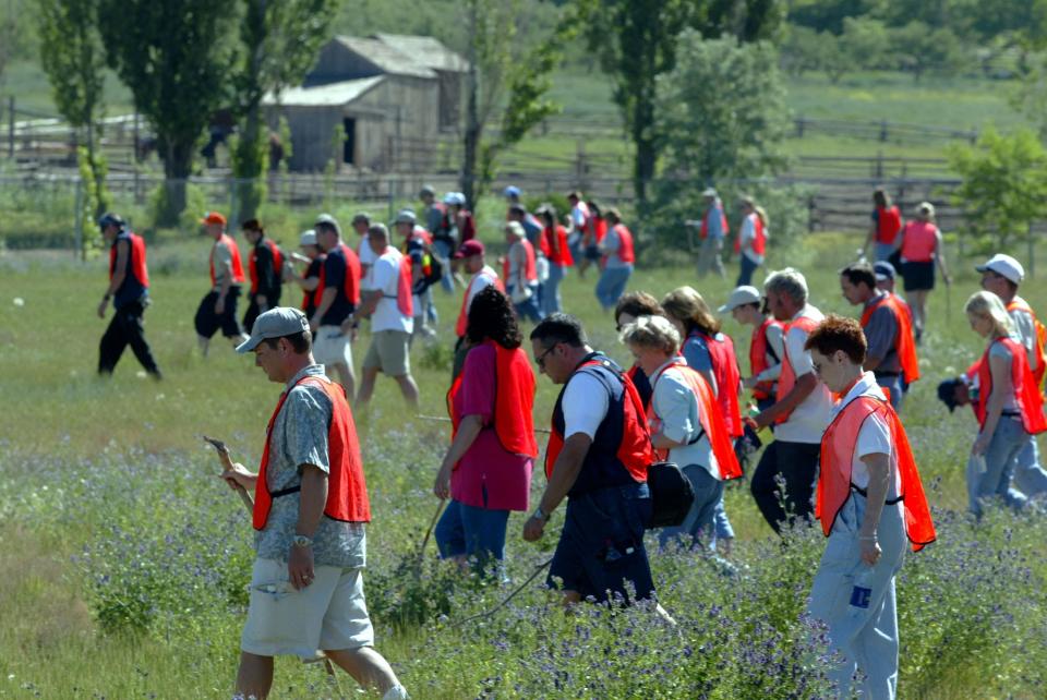 A group of more than 100 volunteers combed the fields in 2002 at This Is The Place State Park searching for clues in the abduction of 14-year-old Elizabeth Smart in Salt Lake City.