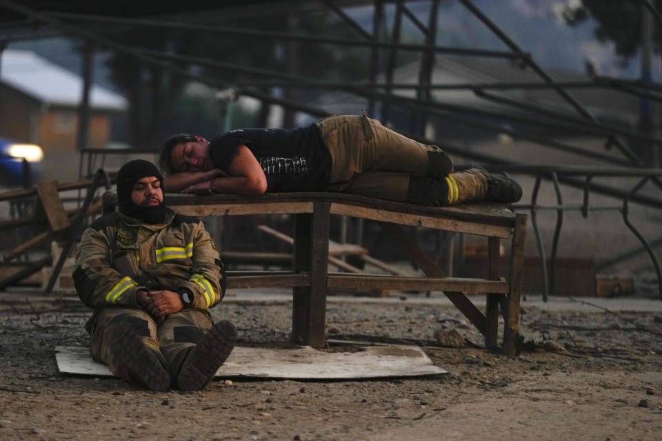 Firefighters take a break from fighting a forest fire in Vina del Mar, Chile, Saturday, Feb. 3, 2024. (AP Photo/Esteban Felix)