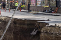 A block of asphalt falls off as rescuers prepare to resume search efforts at a sinkhole in Villa Nueva, Guatemala, Tuesday, Sept. 27, 2022. Search efforts were underway for a mother and daughter who disappeared when their vehicle was swallowed by the massive sinkhole. (AP Photo/Moises Castillo)