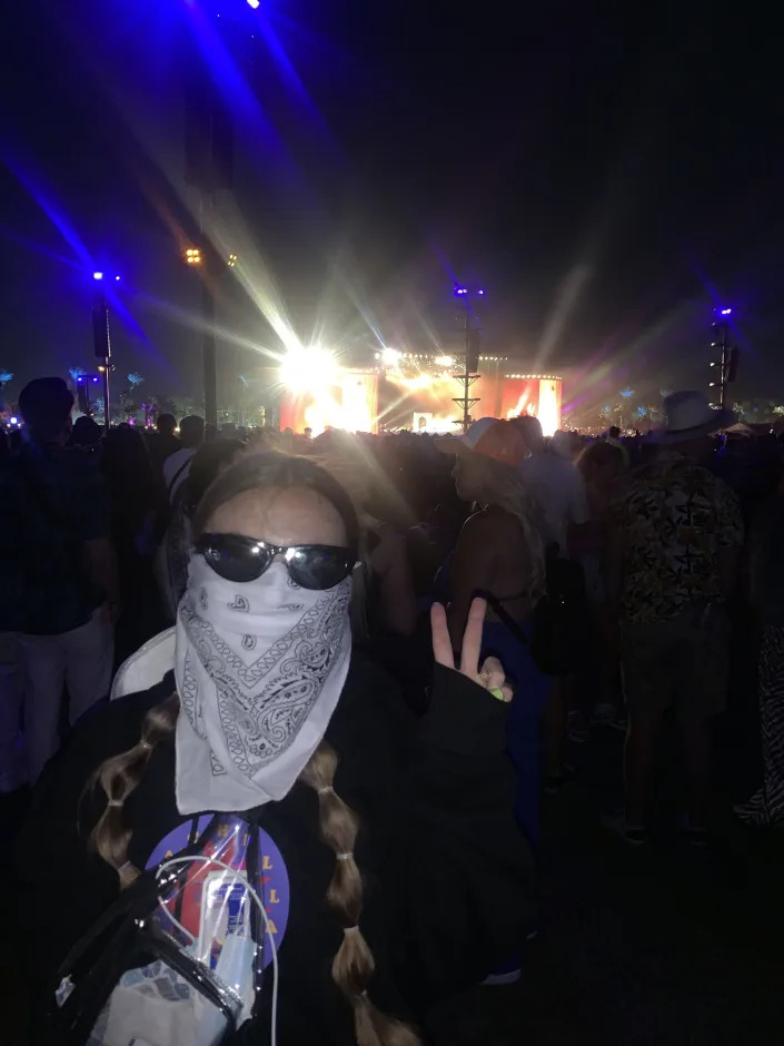 The author with a bandana tied around the lower half of her face an sunglasses in the crowd at the Coachella Stage