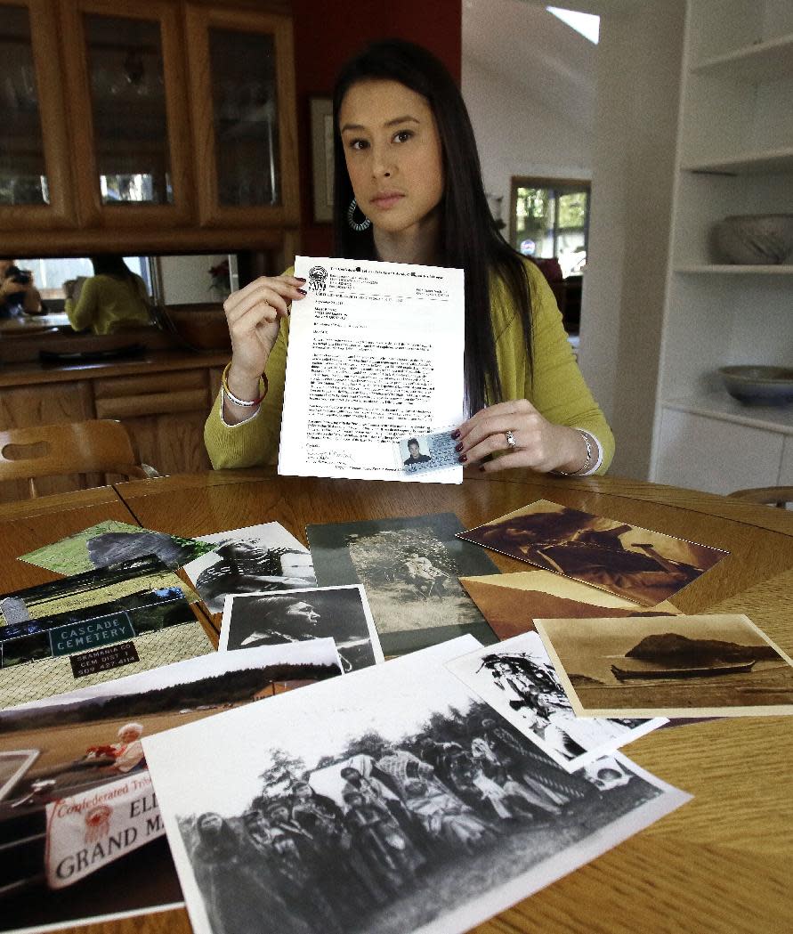 Mia Prickett sits at a table with a collection of family photos and holds her Confederated Tribe of Grande Ronde enrollment card along with a recent notice of potential potential disenrollment from the tribe in Portland, Ore., Thursday, Jan. 16, 2014. Prickett’s ancestor Tumulth, a leader of the Cascade Indians along the Columbia River, was one of the chiefs who signed an 1855 treaty that helped establish the Confederated Tribes of the Grand Ronde in Oregon. But the Grand Ronde now wants to disenroll Prickett and 79 relatives because they no longer satisfy new enrollment requirements. (AP Photo/Don Ryan)