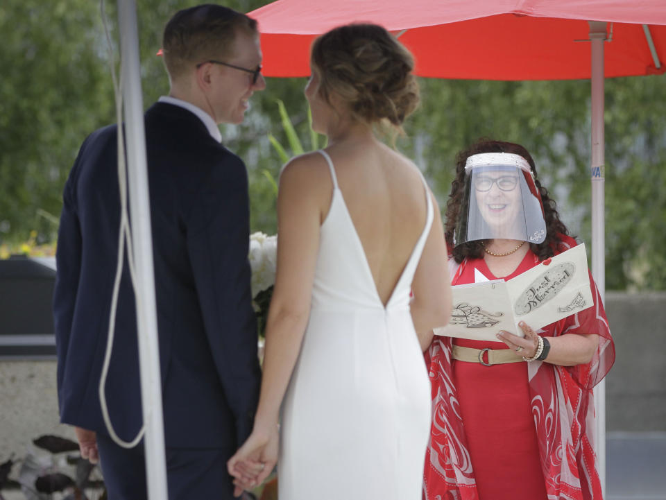 An officiant wearing a face shield hosts an outdoor "micro-wedding" for a couple in Vancouver, Canada, on June 19, 2020. The pilot project was first announced in early May as an alternative for those who may have had to change their wedding plans due to the COVID-19 pandemic. (Photo by Liang Sen/Xinhua via Getty)