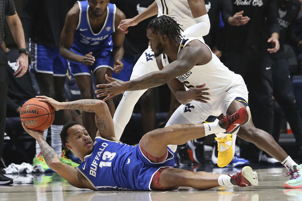 Buffalo guard Zid Powell (13) is defended by West Virginia guard Joe Toussaint (5) during the first half of an NCAA college basketball game in Morgantown, W.Va., Sunday, Dec. 18, 2022. (AP Photo/Kathleen Batten)