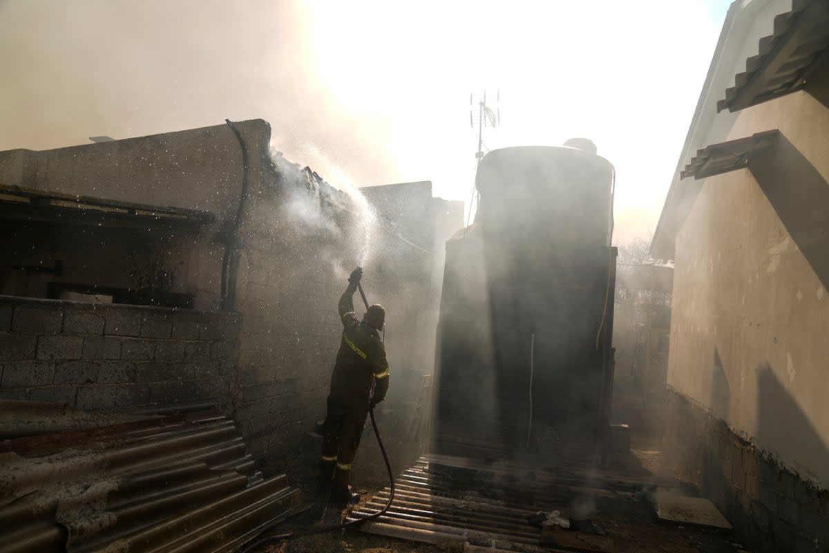 A firefighter aims water with a hose at a house near Loutraki 80 Kilometres west of Athens , on Monday, July 17, 2023 (AP)