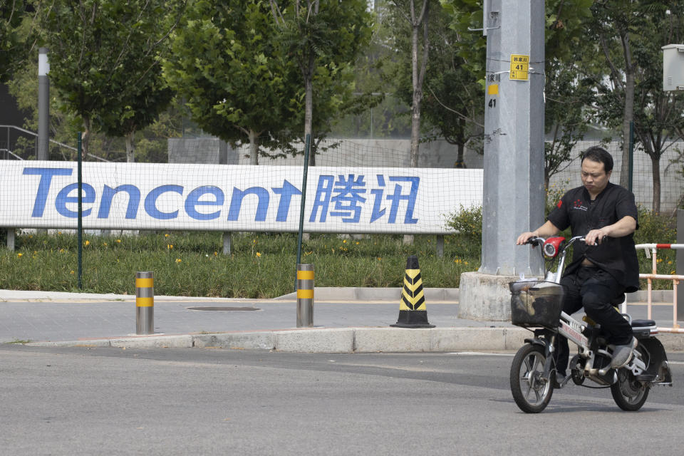 FILE - In this Aug. 7, 2020, file photo, a man rides past the Tencent headquarters in Beijing, China. Companies including internet giants Alibaba and Tencent were fined Wednesday, July 7, 2021, by anti-monopoly regulators in a new move to tighten control over their fast-developing industries. (AP Photo/Ng Han Guan, File)