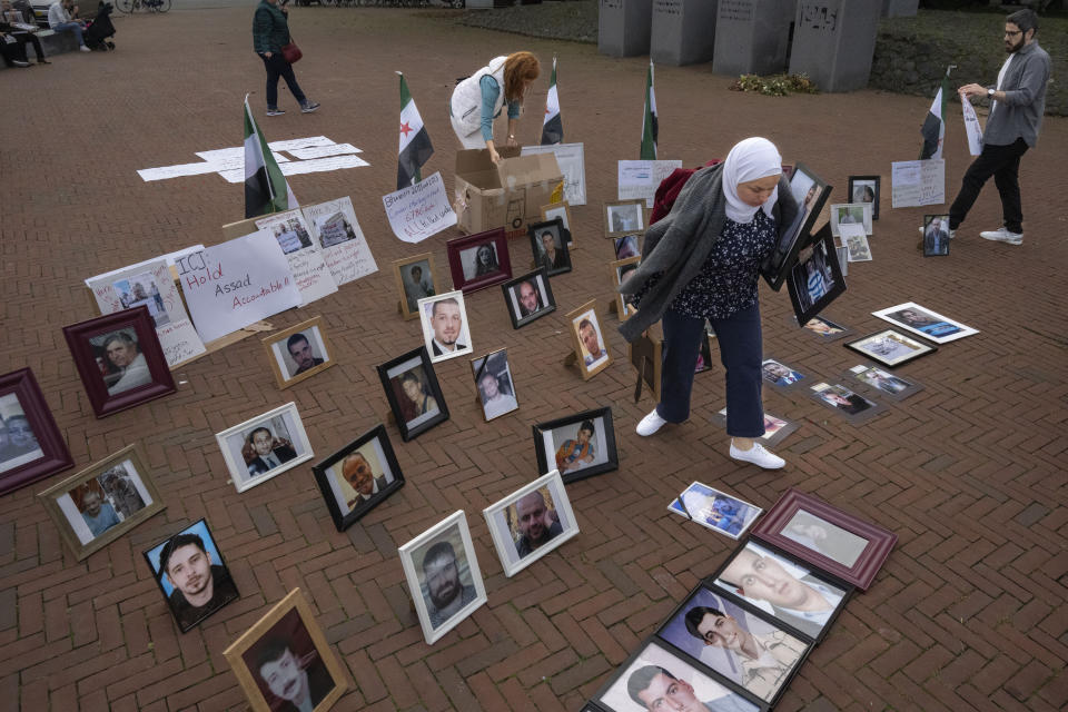 Demonstrators display pictures of people they say disappeared in Syria outside the World Court, where preliminary hearings opened in a case in which the Netherlands and Canada are suing Syria at the International Court of Justice, or World Court, the United Nations' highest judicial organ, in The Hague, Netherlands, Tuesday, Oct. 10, 2023, accusing Damascus of massive human rights violations against its own people. (AP Photo/Peter Dejong)