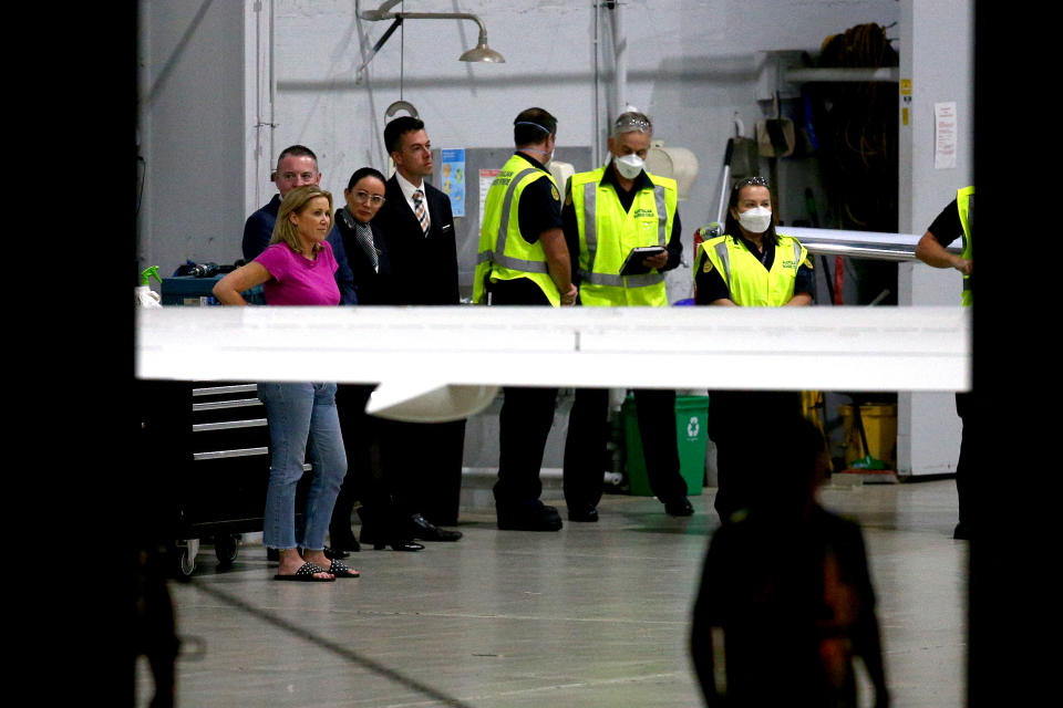 Shane Warne's personal assistant Helen Nolan, pictured here with airport officials waiting for the coffin.