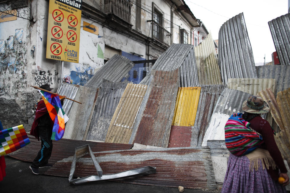 Supporters of former President Evo Morales stand on a barricaded street leading to the presidential palace during a march in La Paz, Bolivia, Thursday, Nov. 14, 2019. Morales resigned and flew to Mexico under military pressure following massive nationwide protests over alleged fraud in an election last month in which he claimed to have won a fourth term in office. (AP Photo/Natacha Pisarenko)