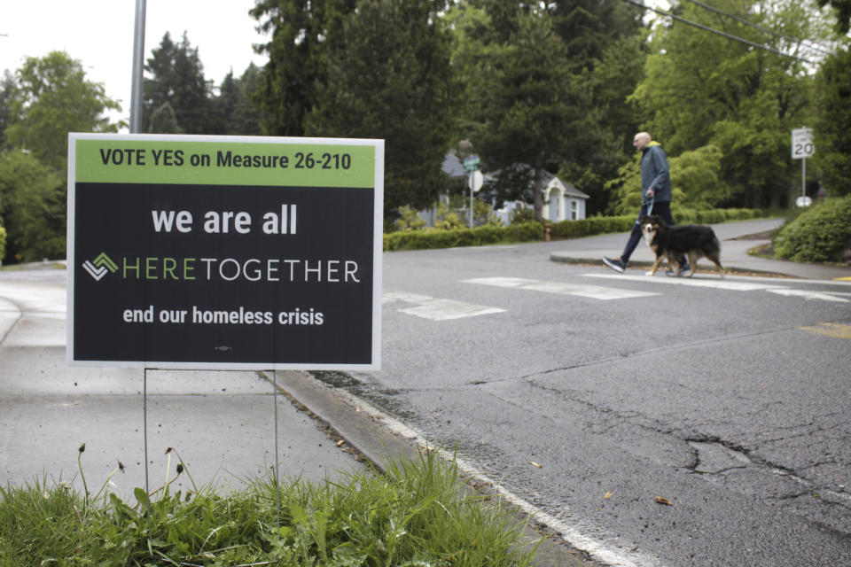 A campaign sign urging people to vote "Yes" on Measure 26-210, which would approve taxes on personal income and business profits to raise $2.5 billion over a decade to fight homelessness, is displayed near a street, Thursday, May 14, 2020, in Portland, Ore. Voters in metropolitan Portland will vote on the measure Tuesday, May 19, , and the result of the ballot question amid the coronavirus pandemic will be instructive for other West Coast cities that are struggling to address burgeoning homeless populations as other revenue streams dry up. (AP Photo/Gillian Flaccus)