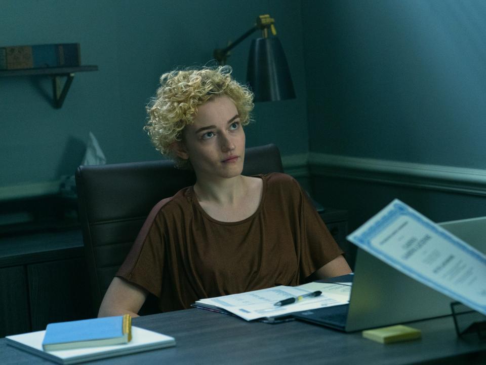 Julia Garner sitting at desk in "Ozark"