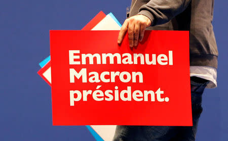 A technician holds placards in support of Emmanuel Macron, head of the political movement En Marche ! (Onwards !) and candidate for the 2017 presidential election, before a campaign rally in Pau, Southwestern France, April 12, 2017. REUTERS/Regis Duvignau