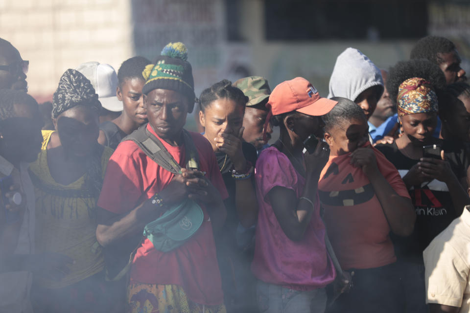 Bystanders look at the bodies of alleged gang members that were set on fire by a mob after they were stopped by police while traveling in a vehicle in the Canape Vert area of Port-au-Prince, Haiti, Monday, April 24, 2023. (AP Photo/Odelyn Joseph)