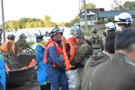 Rescue workers help residents evacuate an area after a typhoon swept through Kawagoe, Saitama prefecture