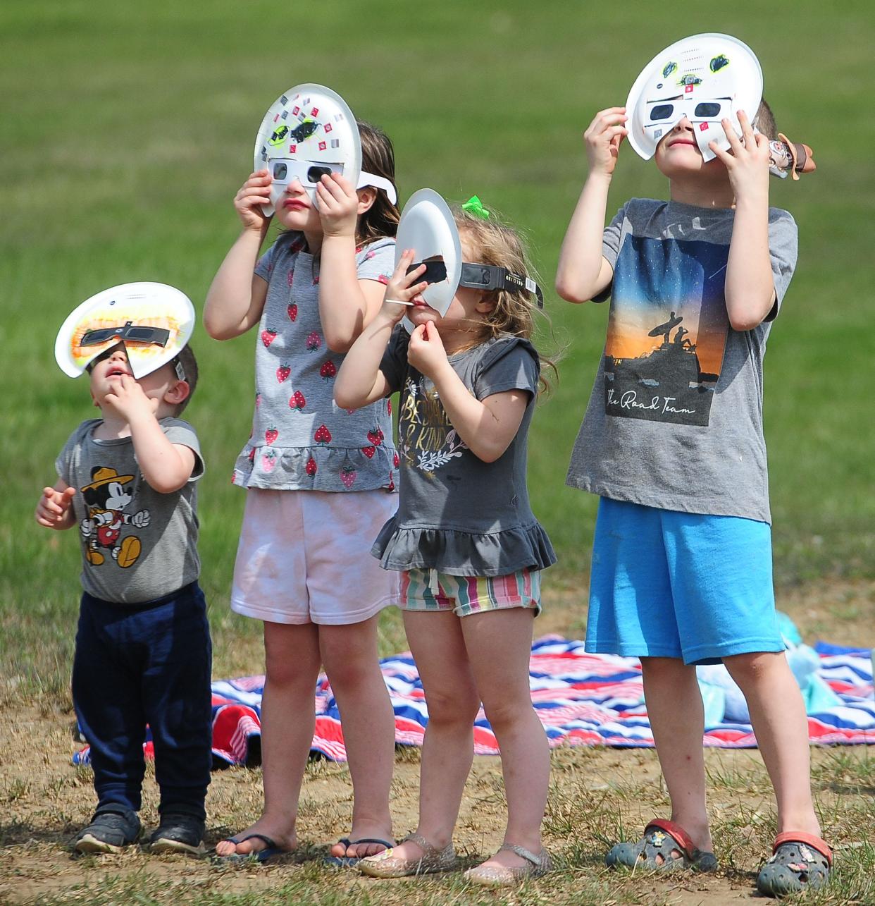 Calvin Baia, 1, Stella Baia, 5, Millie Baia, 3, and Auggie Baia, 7, view the start of the eclipse Monday, April 8, 2024, during The Total Solar Eclipse Watch Party at Butler Rodman Park in Alliance.