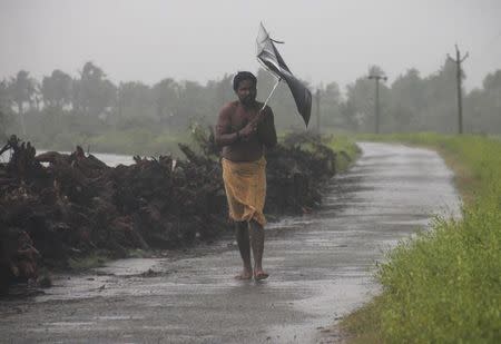 A man struggles with an umbrella in strong winds and rain caused by Cyclone Hudhud in Gopalpur in Ganjam district in Odisha October 12, 2014. REUTERS/Stringer